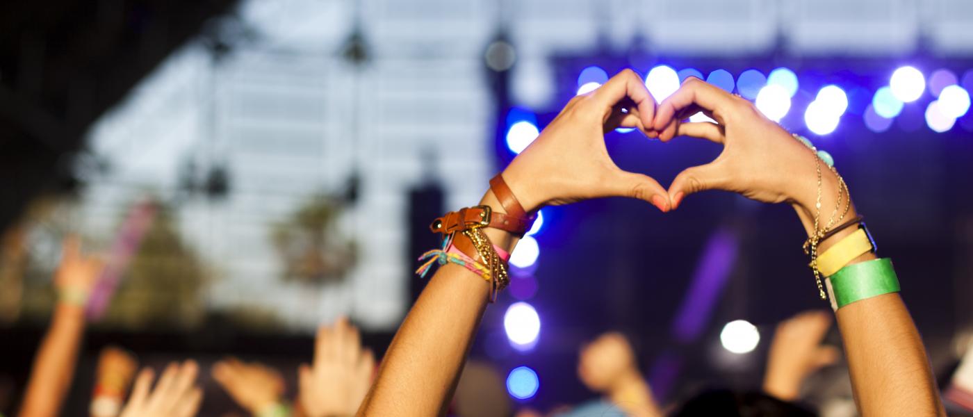 Person i publik på koncert gör hjärta med händerna