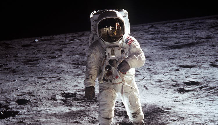 Austronaut med rymddräkt står på månens yta